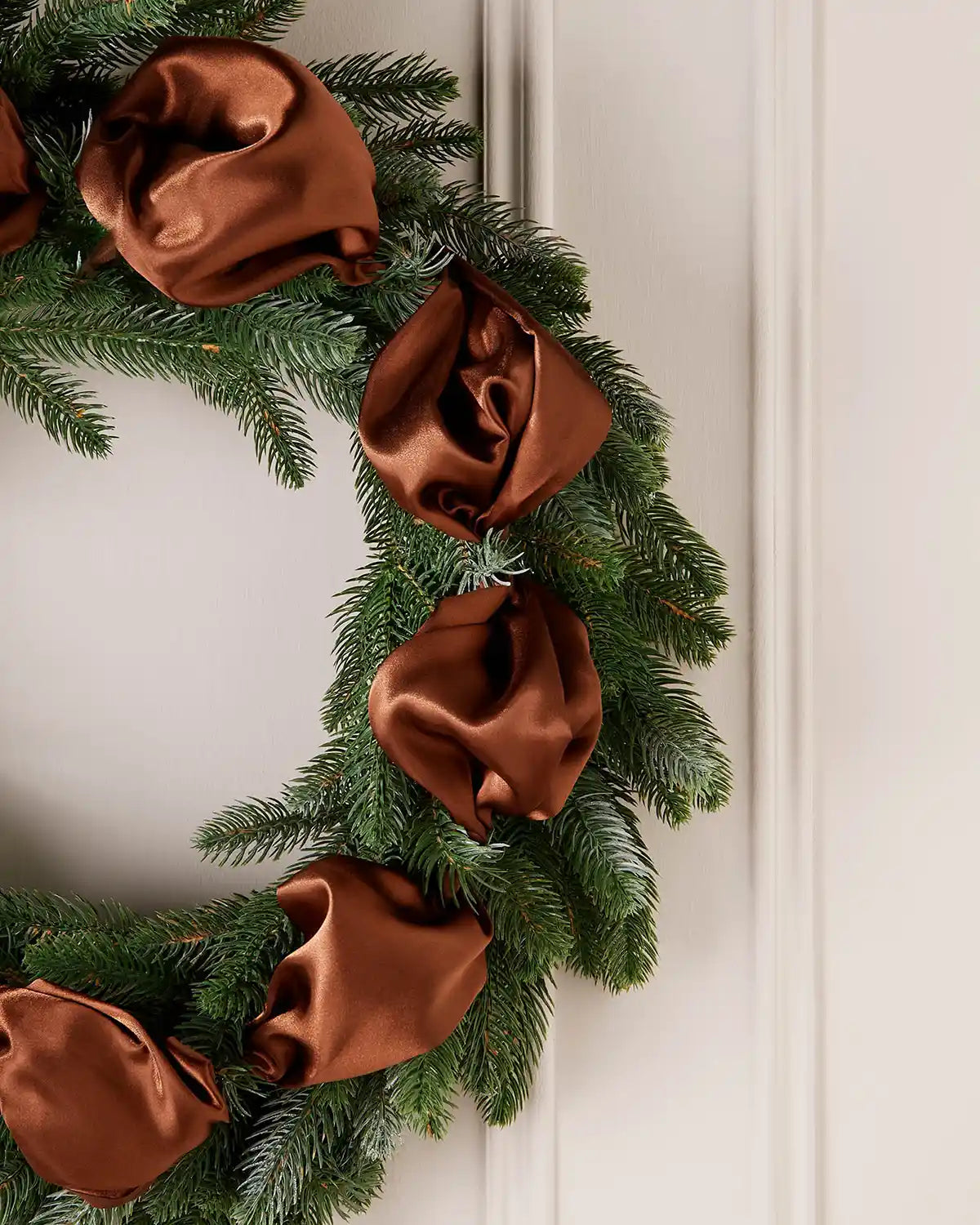 Christmas wreath with espresso ribbons on a white door