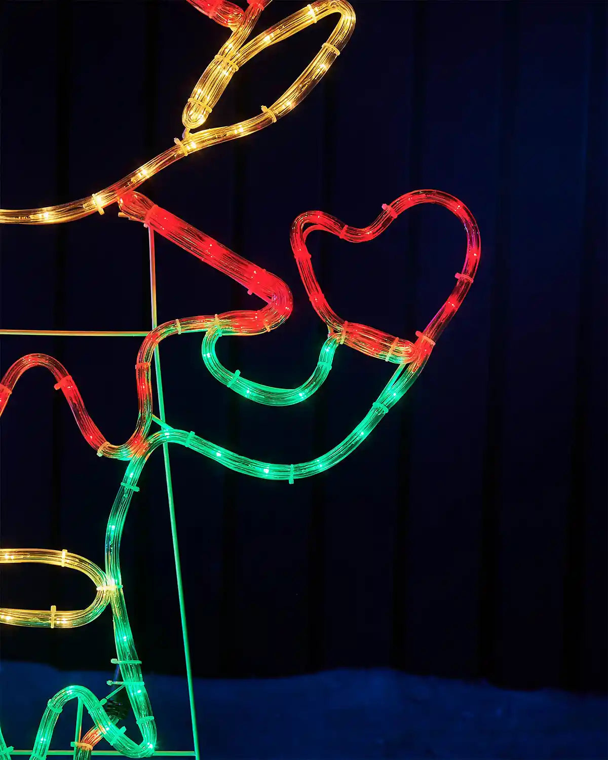 Decorative light sculpture of an elf with red, green, and gold colours on a dark background.