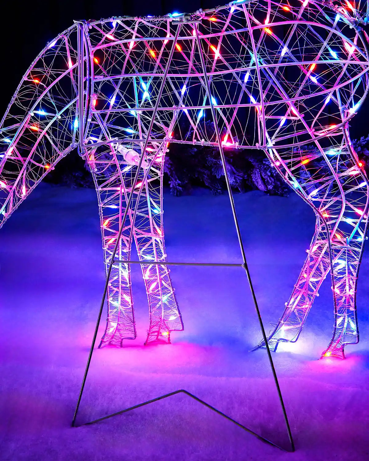 Close up of legs on a Decorative deer sculpture with colourful Aroura lights against a dark background