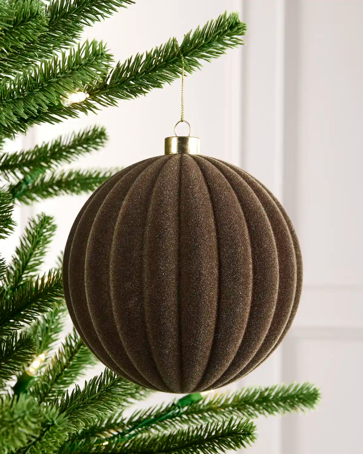 15 cm Mocha oversized velvet Ribbed bauble hanging from a Christmas tree with a gold cap.
