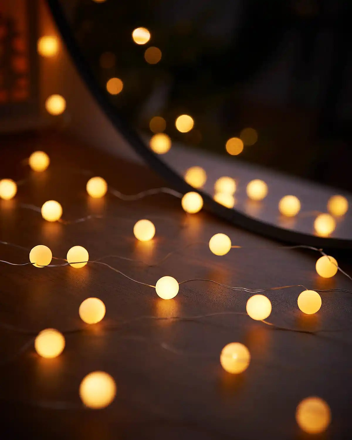 Warm white berry strong lights on a wooden table with a mirror in background