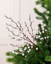 White Berry Christmas Tree Pick placed in a Christmas tree with a blurry cream background