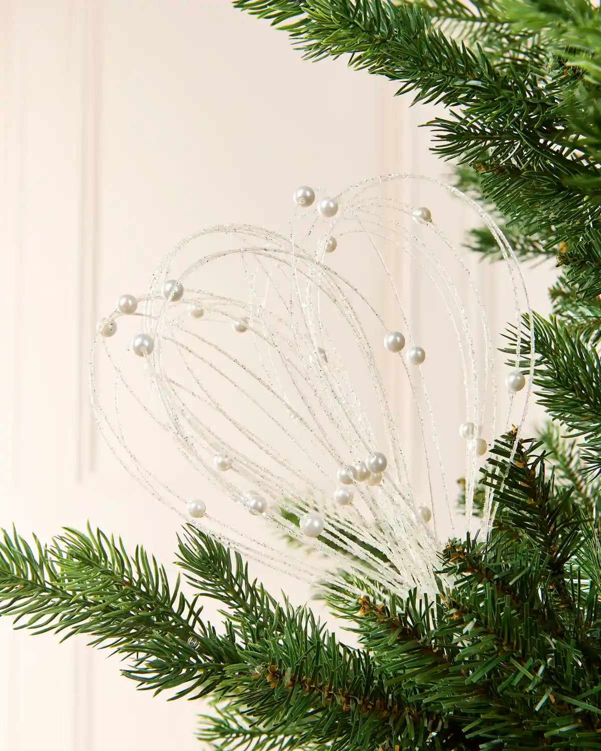 White Glitter Nest Christmas Tree Pick placed in green Christmas tree branches with a cream background
