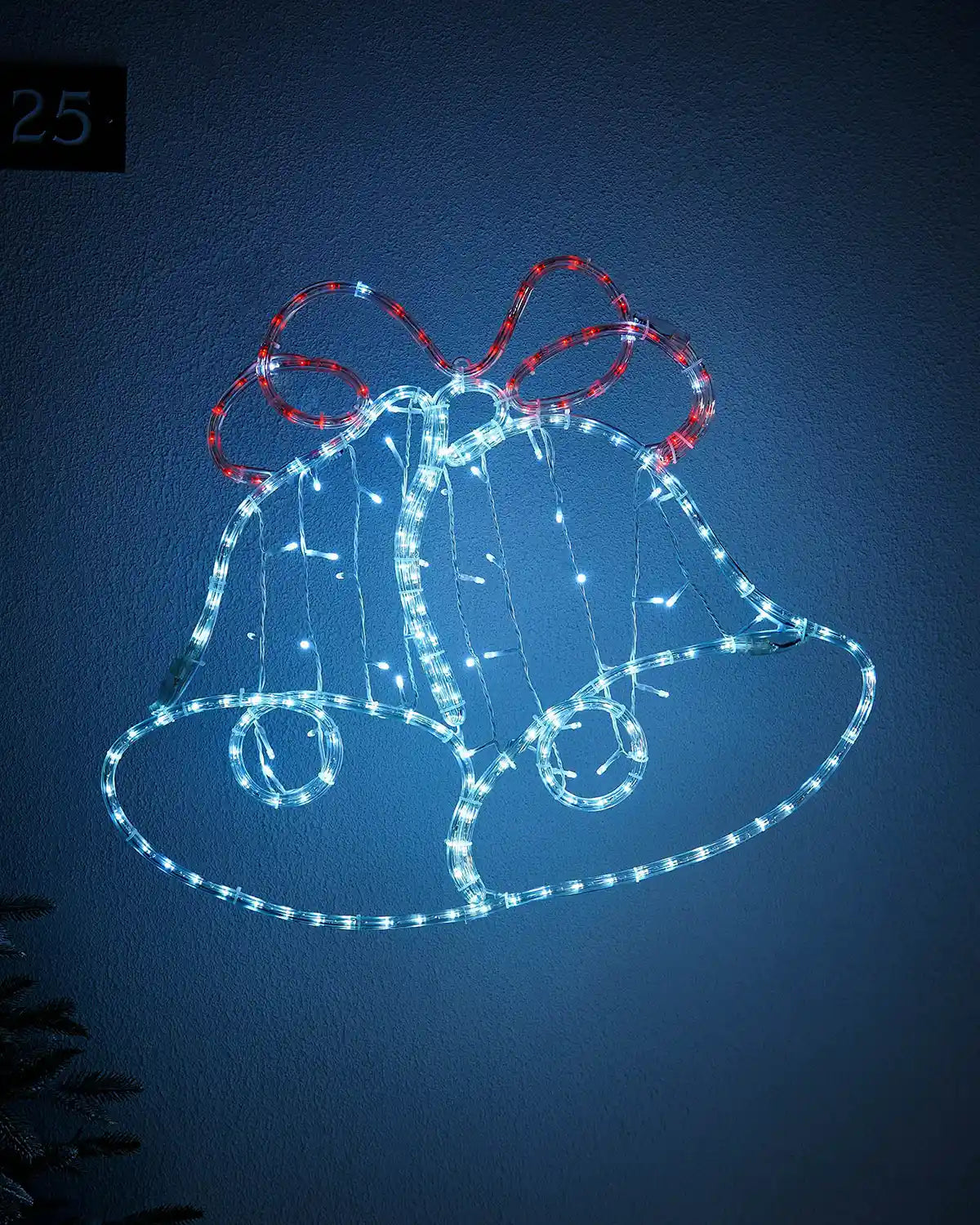 White and Red Light up Christmas bell silhouette on a light coloured wall outside