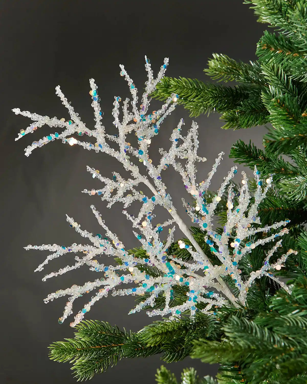 White beaded crystal spray attached to Christmas tree in front of grey wall background