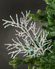 White beaded crystal spray attached to Christmas tree in front of grey wall background