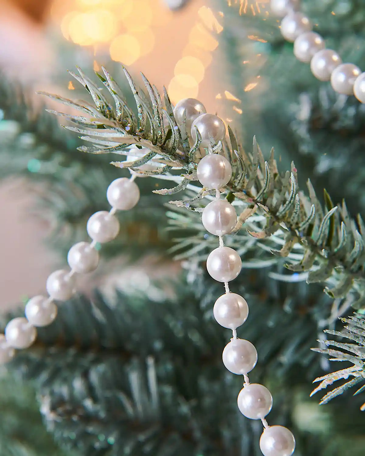 White beaded garland on a Christmas tree with a blurred background