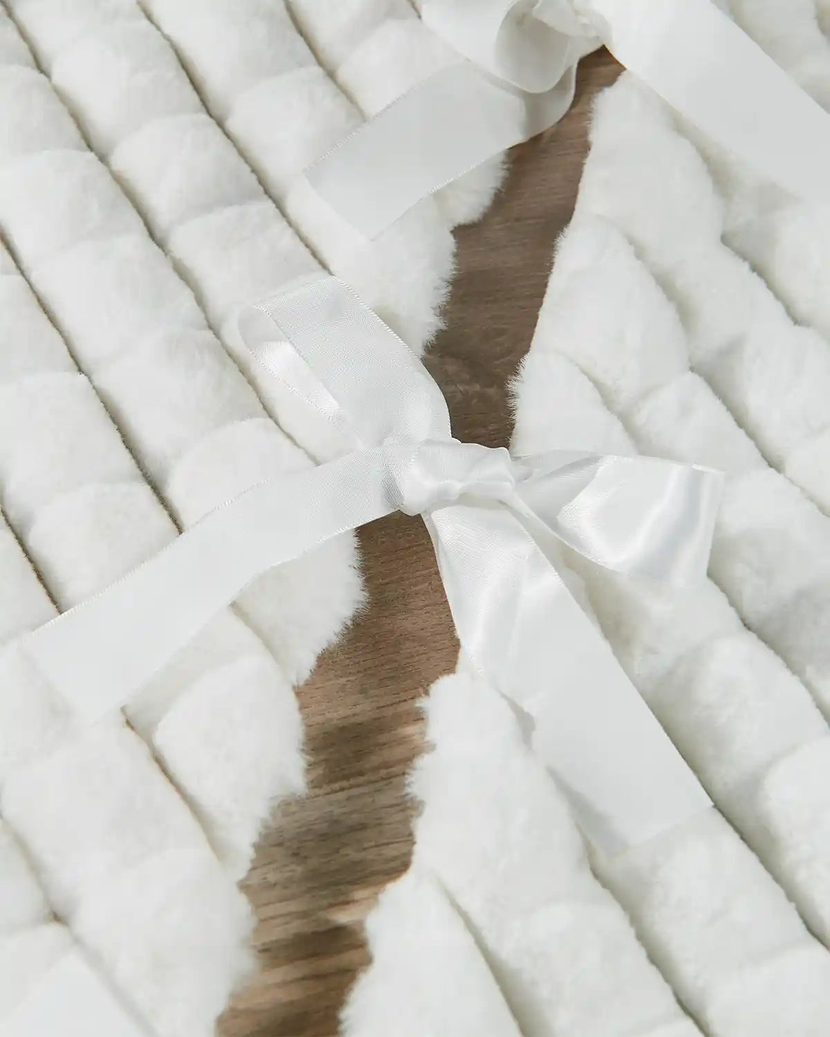 Close-up of the back of the white diamond faux fur tree skirt, highlighting the ribbon ties 