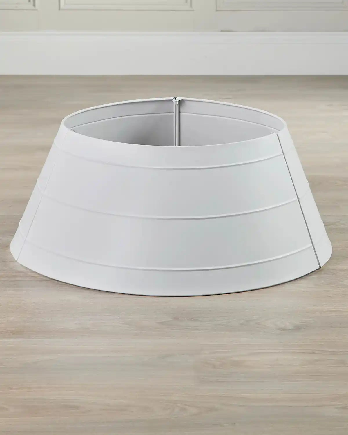 White metal tree skirt presented without tree on light wood flooring highlighting canonical shape