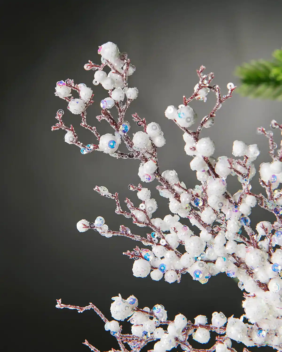 Close-up of white pearls crystal spray in front of grey wall background highlighting iridescent sequins