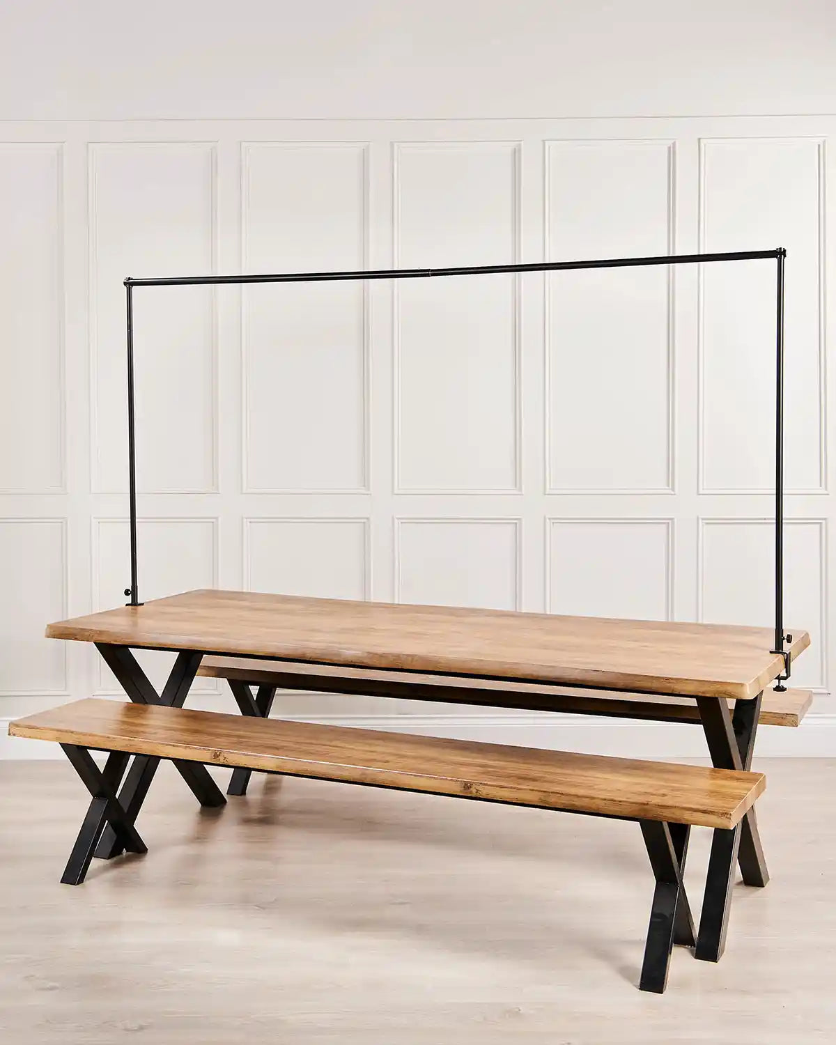 Wooden dining table with a black bar over the top against a cream panel background