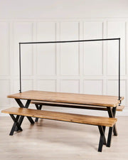 Wooden dining table with a black bar over the top against a cream panel background