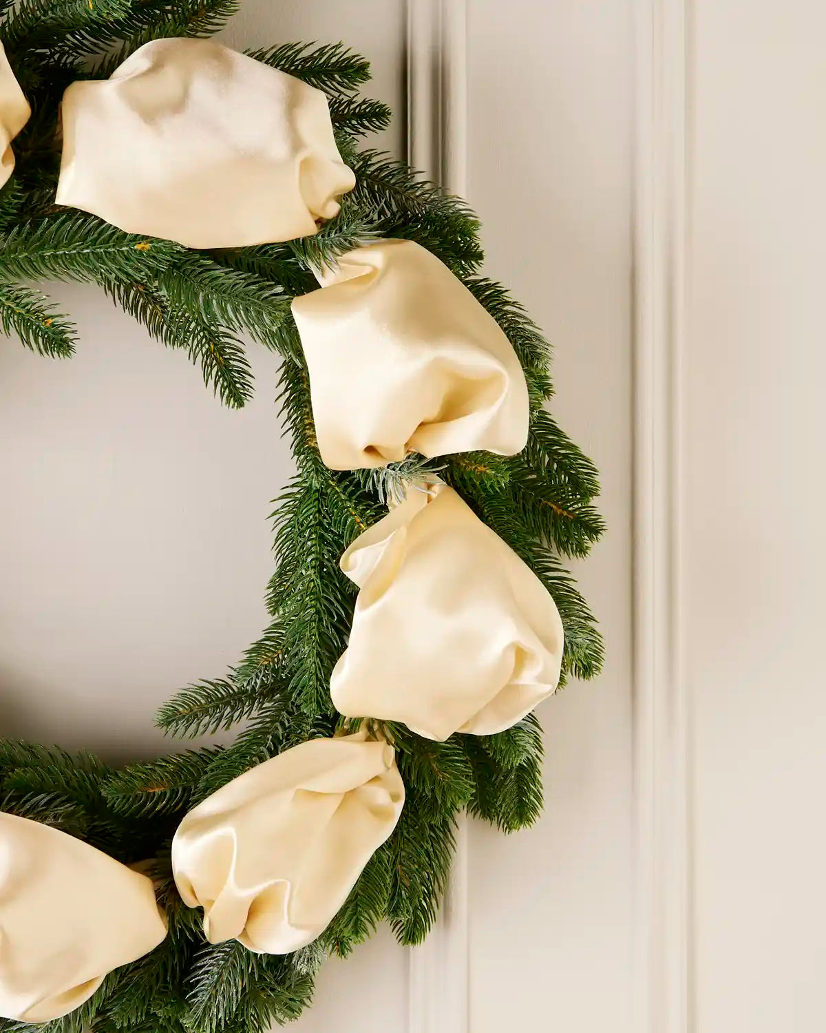 Christmas wreath with latte ribbons on a white door
