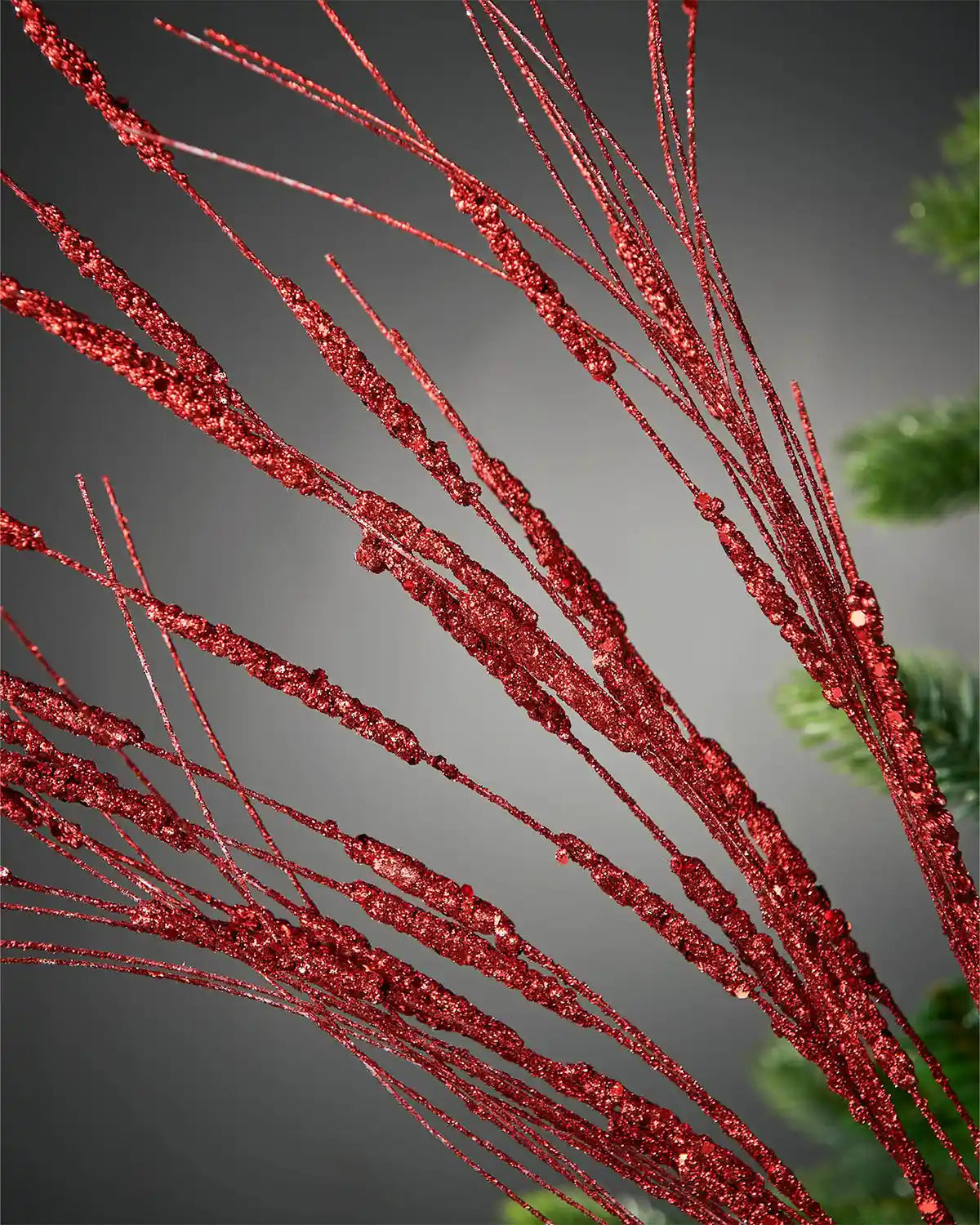 Zoomed-in image of 100cm red glitter wispy spray in Christmas tree in front of grey background
