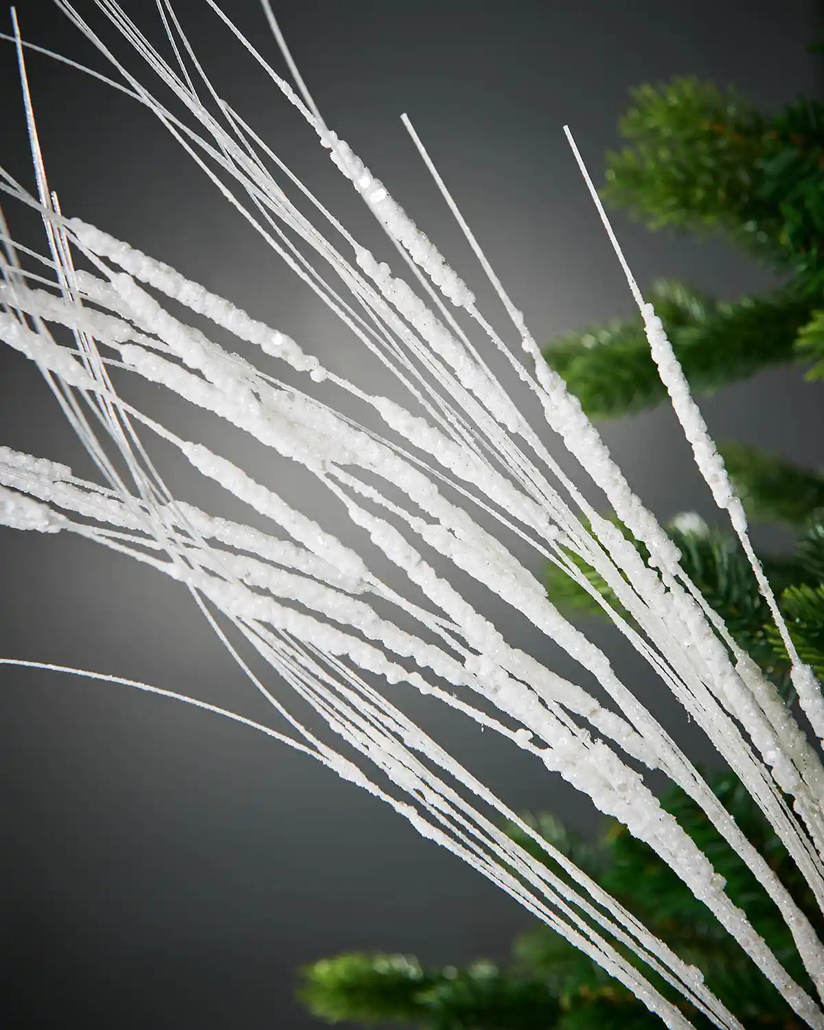 Zoomed-in image of 100cm white glitter tree spray in front of grey background highlighting sparkle