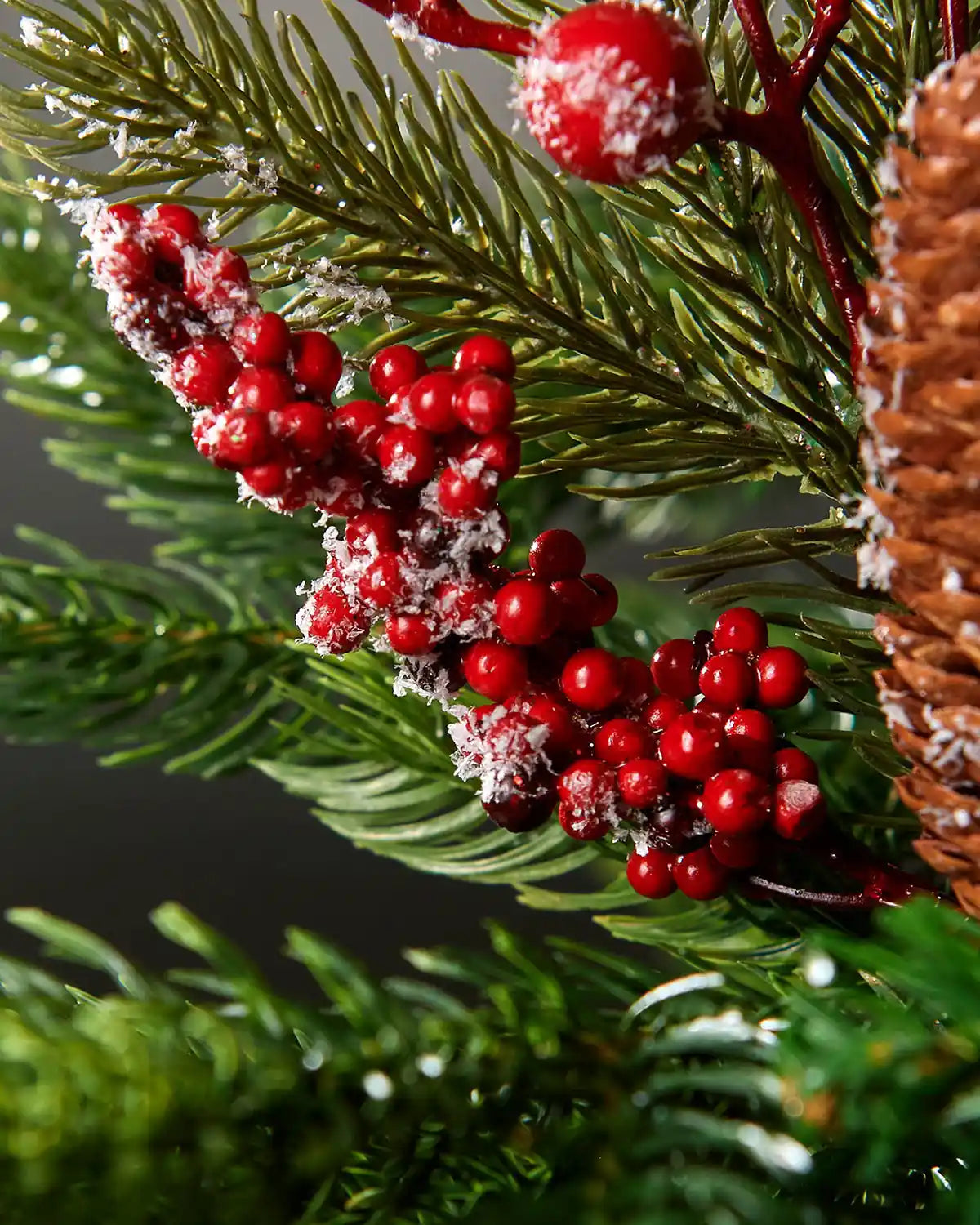 Zoomed-in image of frosted red berries and pinecone pick attached to Christmas tree