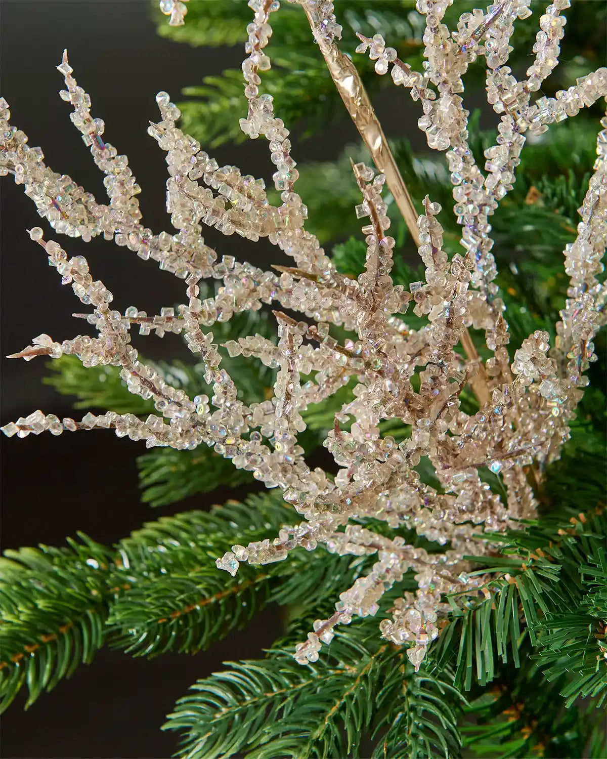 Zoomed-in image of gold beaded crystal spray attached to Christmas tree  in front of grey wall background