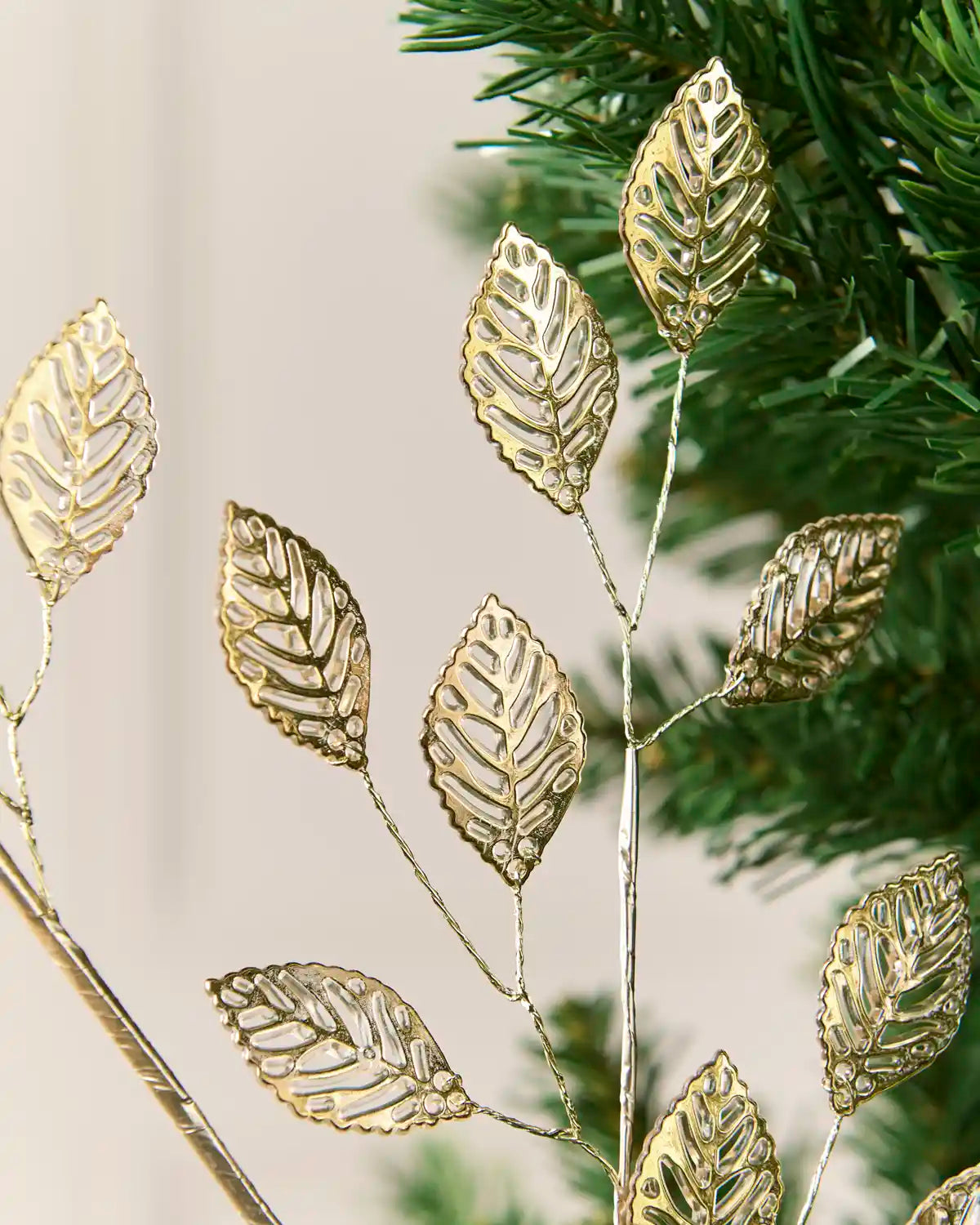 Close-up of antique gold openwork leaves attached to slender metallic branches.