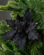 25 cm artificial black poinsettia flower displayed in a Christmas tree, with velvet-textured petals and glitter detail.