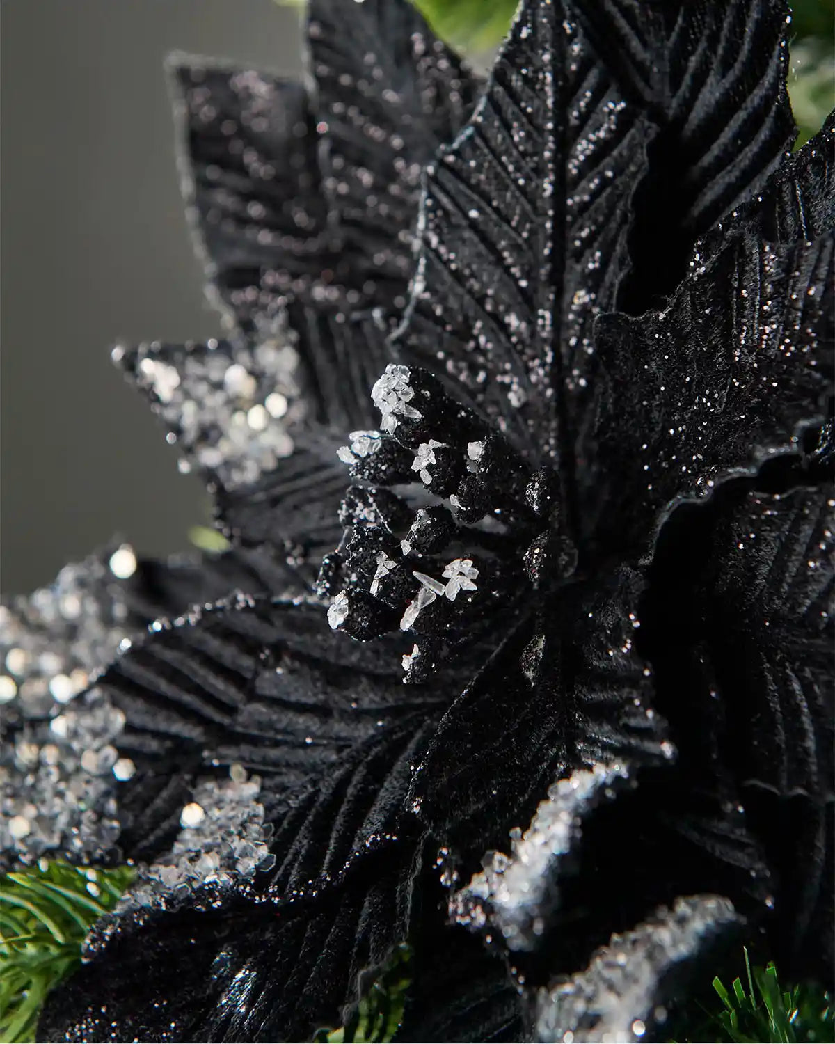 Close-up of a 28 cm artificial black poinsettia flower showing velvet-effect petals, silver glitter and clear jewel details.