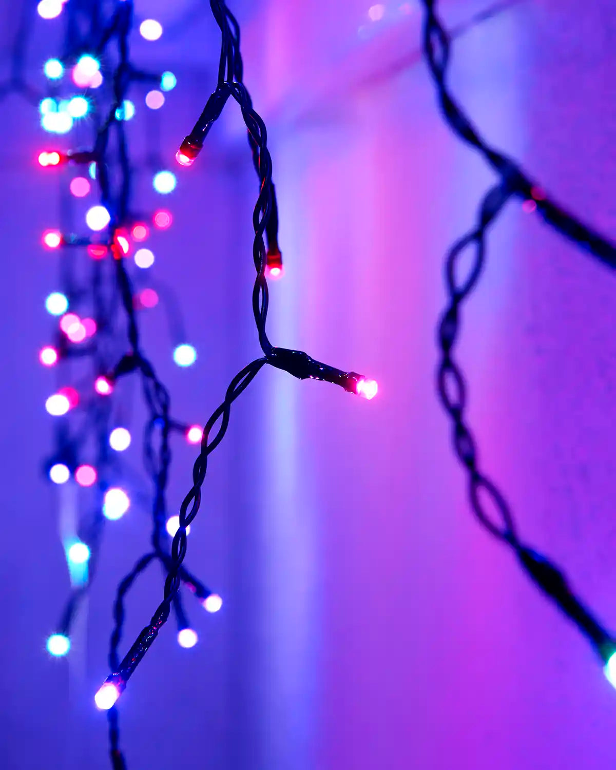 Close-up of Aurora icicle lights on black cable against an exterior wall.