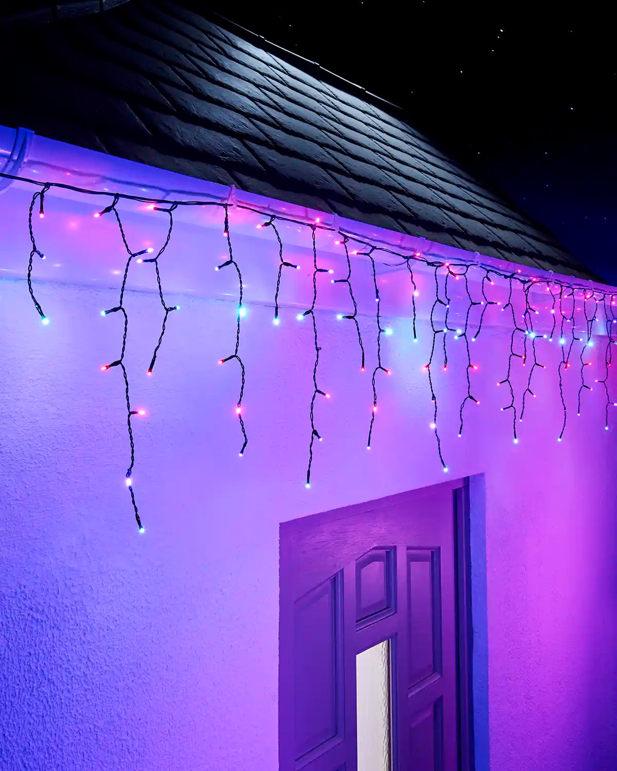Aurora icicle lights on black cable displayed along an outdoor roofline at night.