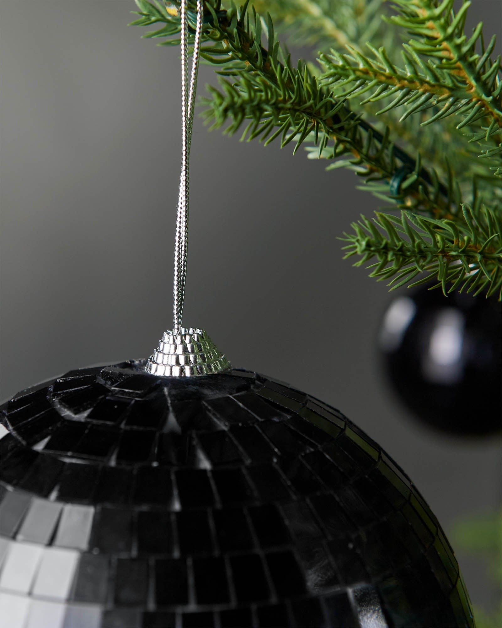 Close-up of the silver hanging string and top cap on a black 15cm disco ball bauble.
