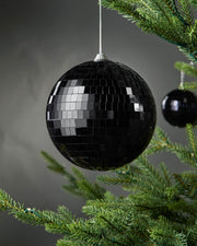 Black 15cm oversized disco ball bauble hanging on a Christmas tree.