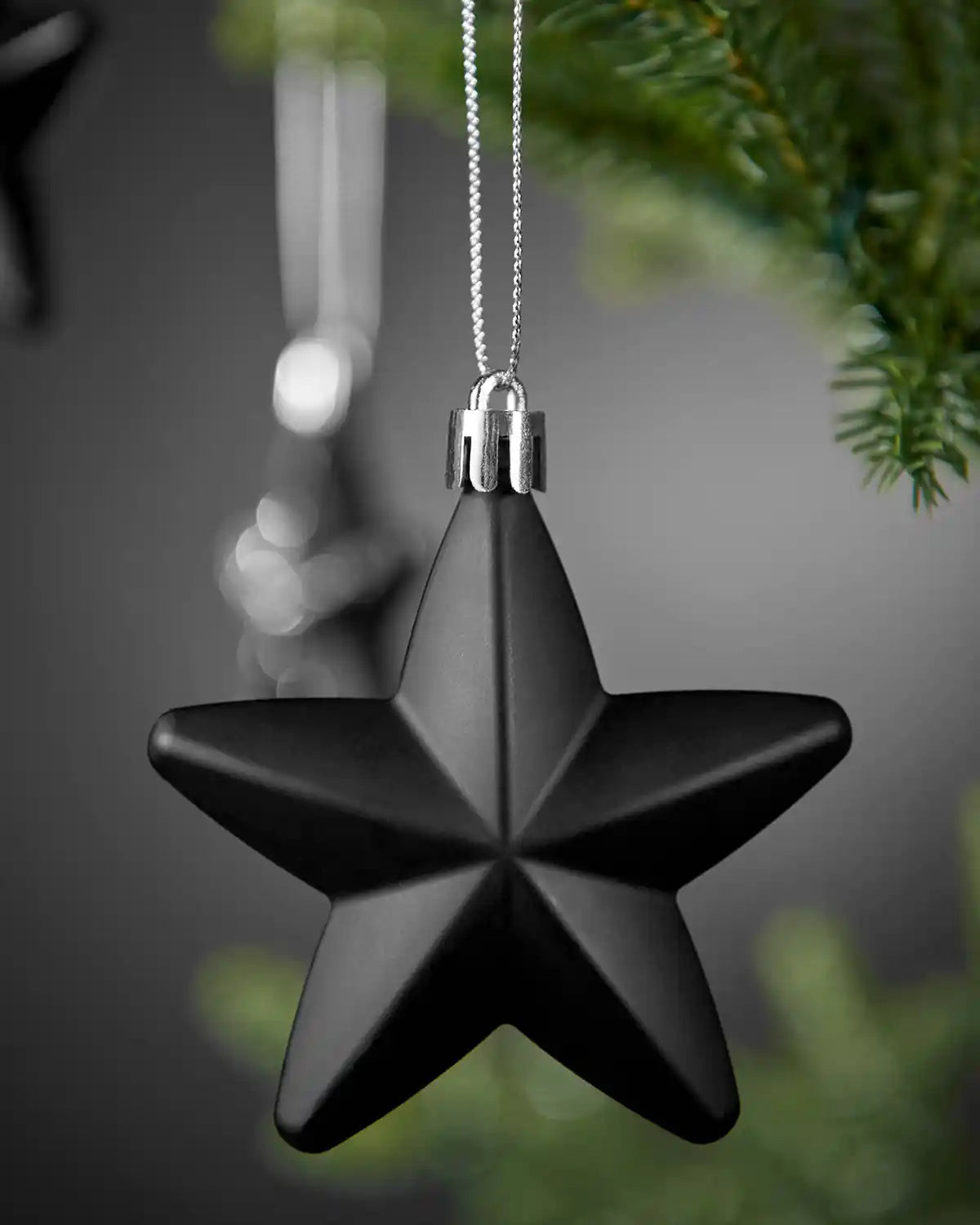 Close-up of a matte black 7cm hanging star with silver string.