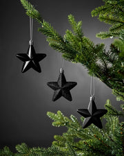 Black 7cm hanging star decorations in shiny, glitter and matte finishes displayed on a Christmas tree.