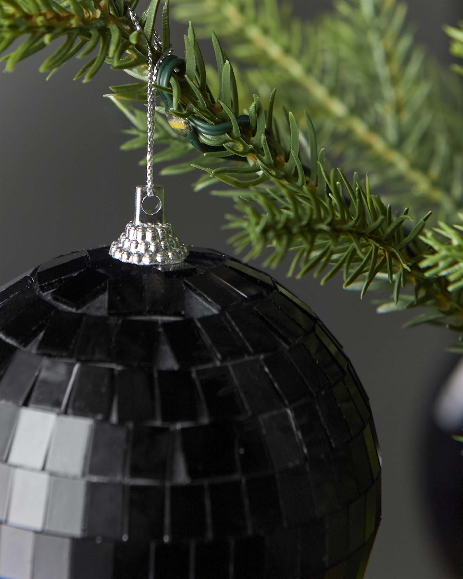 Close-up of the hanging string and top cap on a black 8cm disco ball bauble.