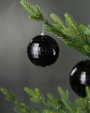 Black 8cm disco ball bauble hanging on a Christmas tree branch.