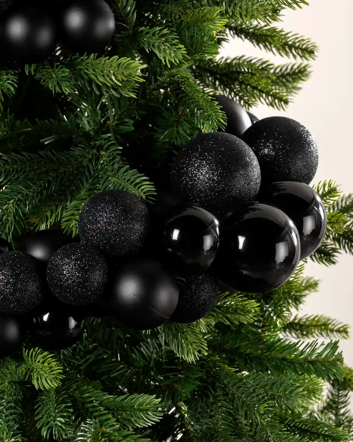Close-up of black baubles showing shiny, matt and glitter finishes on a Christmas tree.