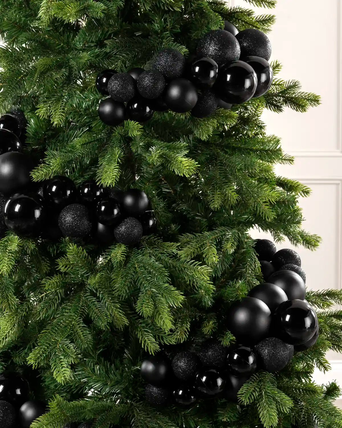 Close-up of black bauble cluster arch on a Christmas tree showing mixed sizes and finishes.
