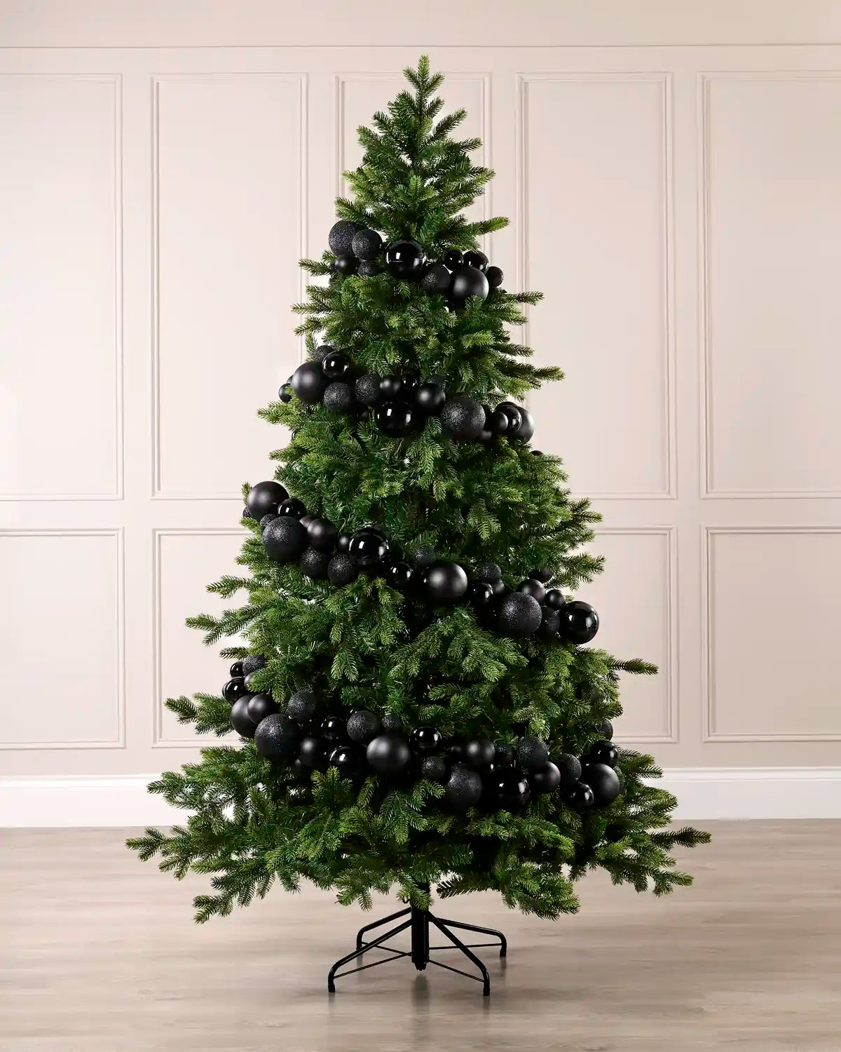 Black bauble garland wrapped around a green Christmas tree with shiny, matt and glitter baubles.