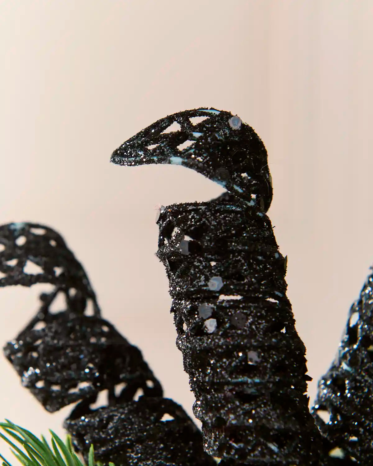 Detailed view of a black glitter spiral pick showing its curled shape and textured reflective finish.
