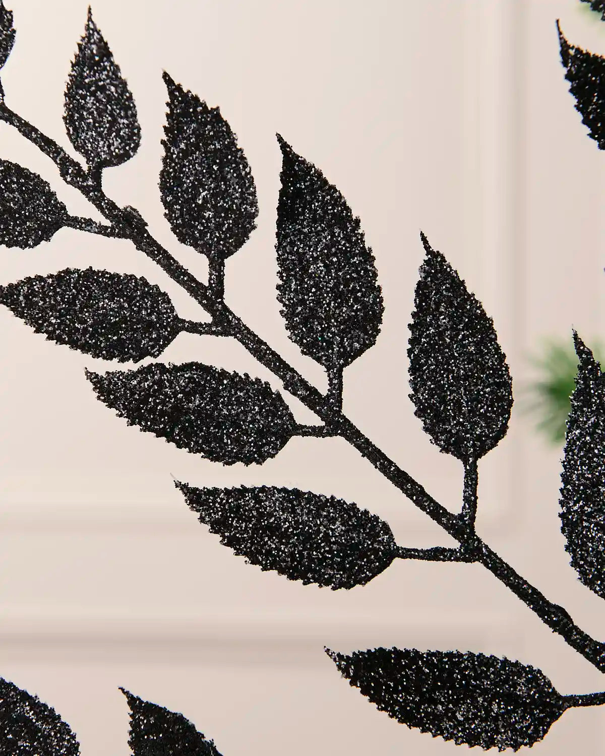 Close-up of the glitter-coated black leaves on the Christmas tree spray.