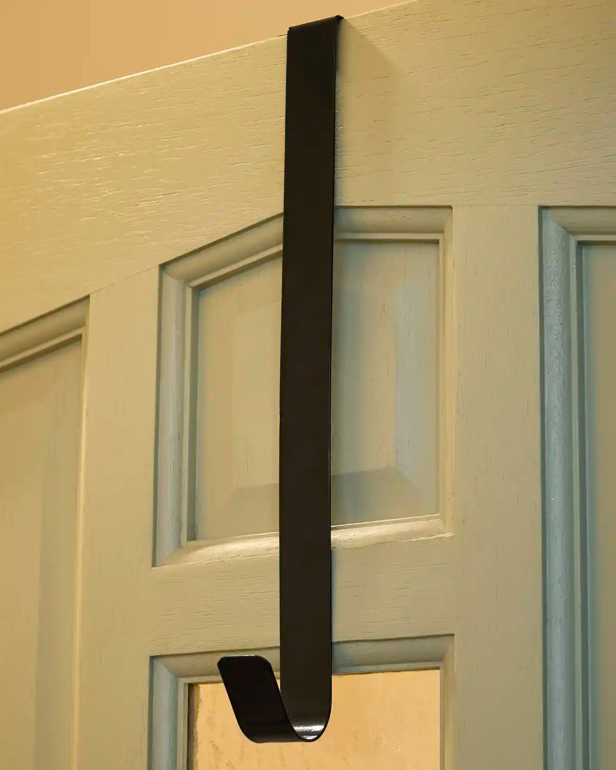 Black 38 cm metal wreath hanger fitted over the top of a white door.