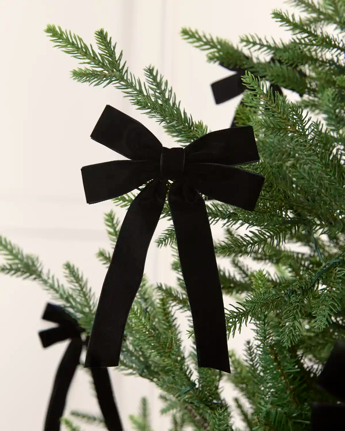 Black velvet double bow displayed among matching bows on a Christmas tree.