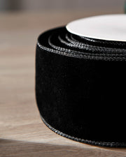 Close-up of black velvet ribbon on a roll, showing the soft texture and wired edge.