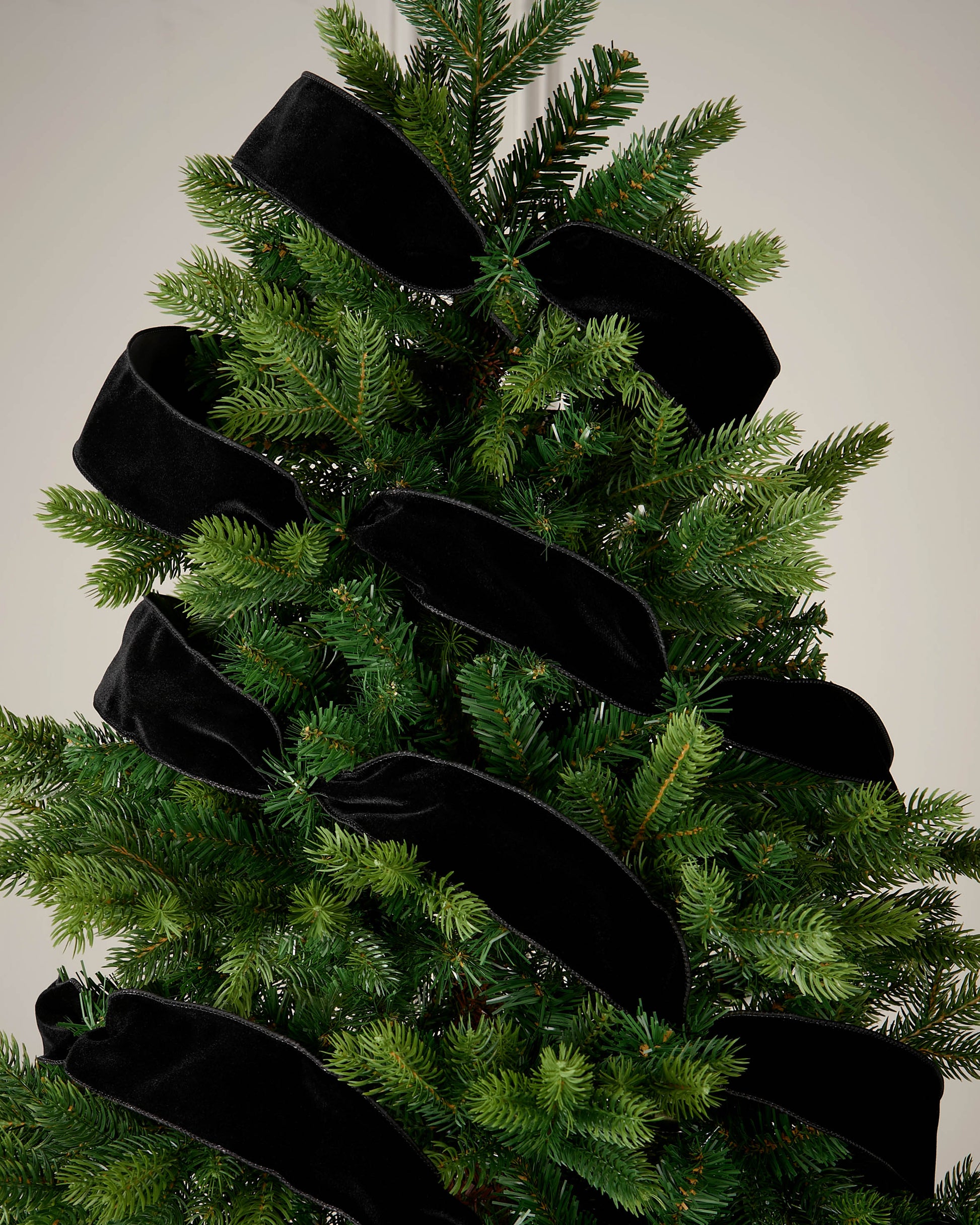 Black velvet ribbon wrapped around a Christmas tree as a soft festive decoration.