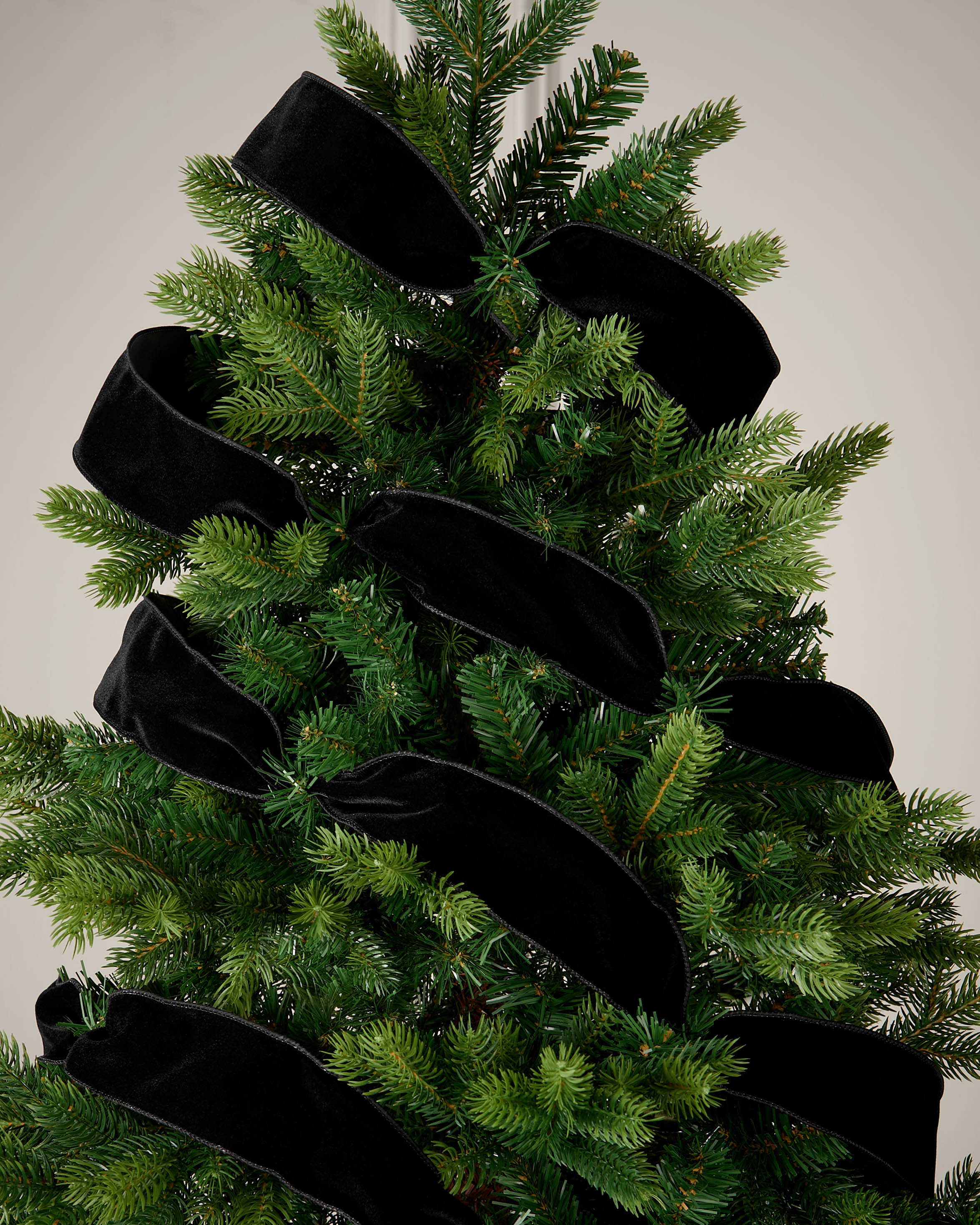 Black velvet ribbon wrapped around a Christmas tree as a soft festive decoration.