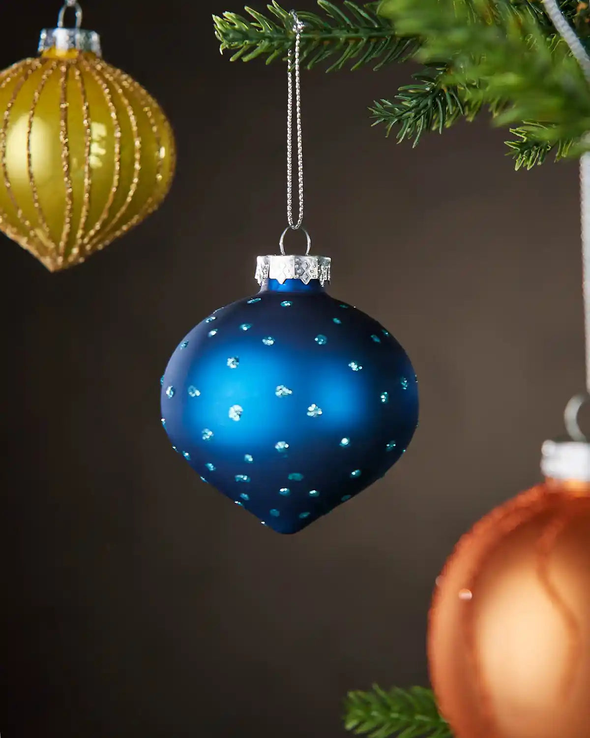 Blue glass round bauble hanging on Christmas tree