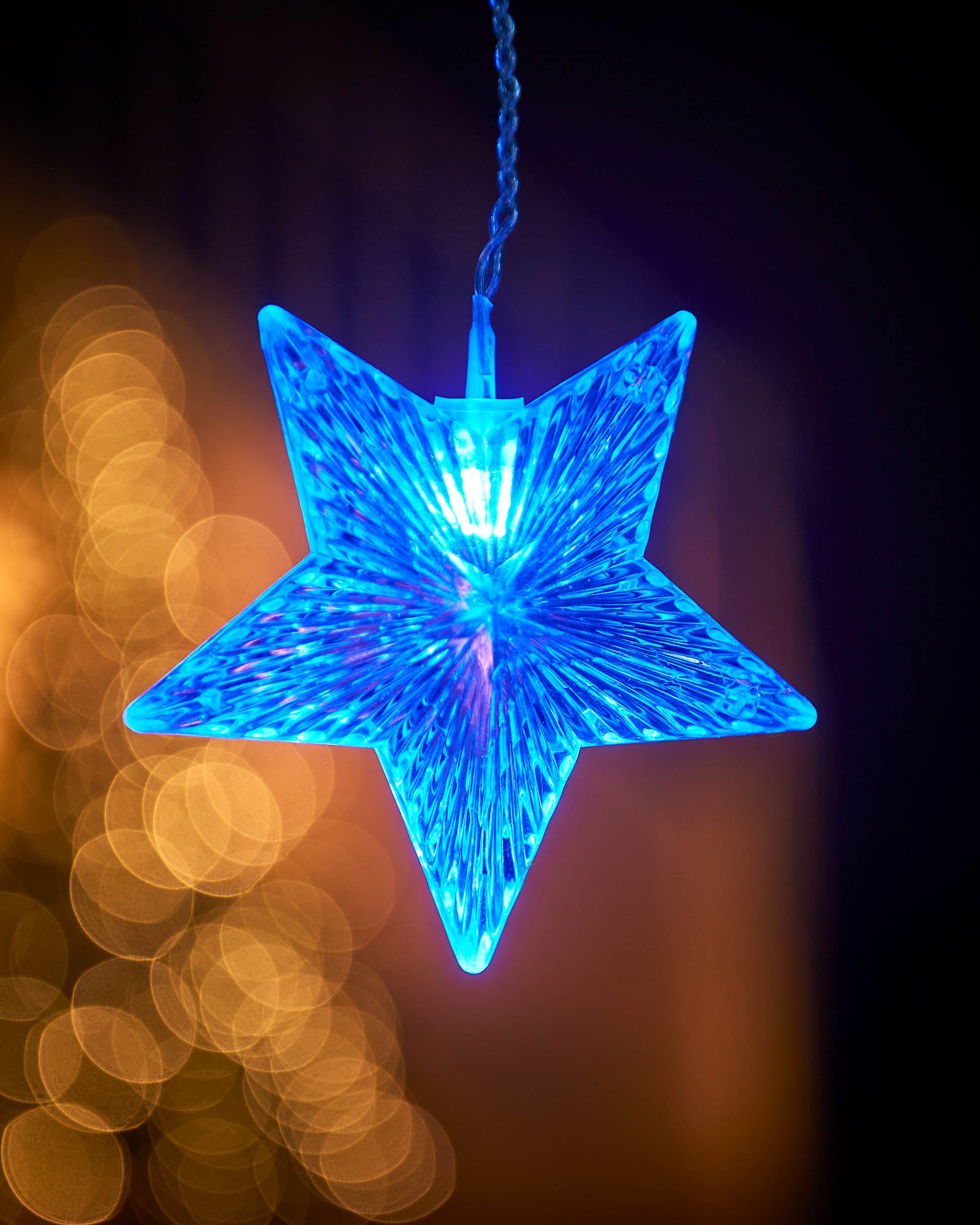 Close-up of a glowing blue star on star curtain net lights