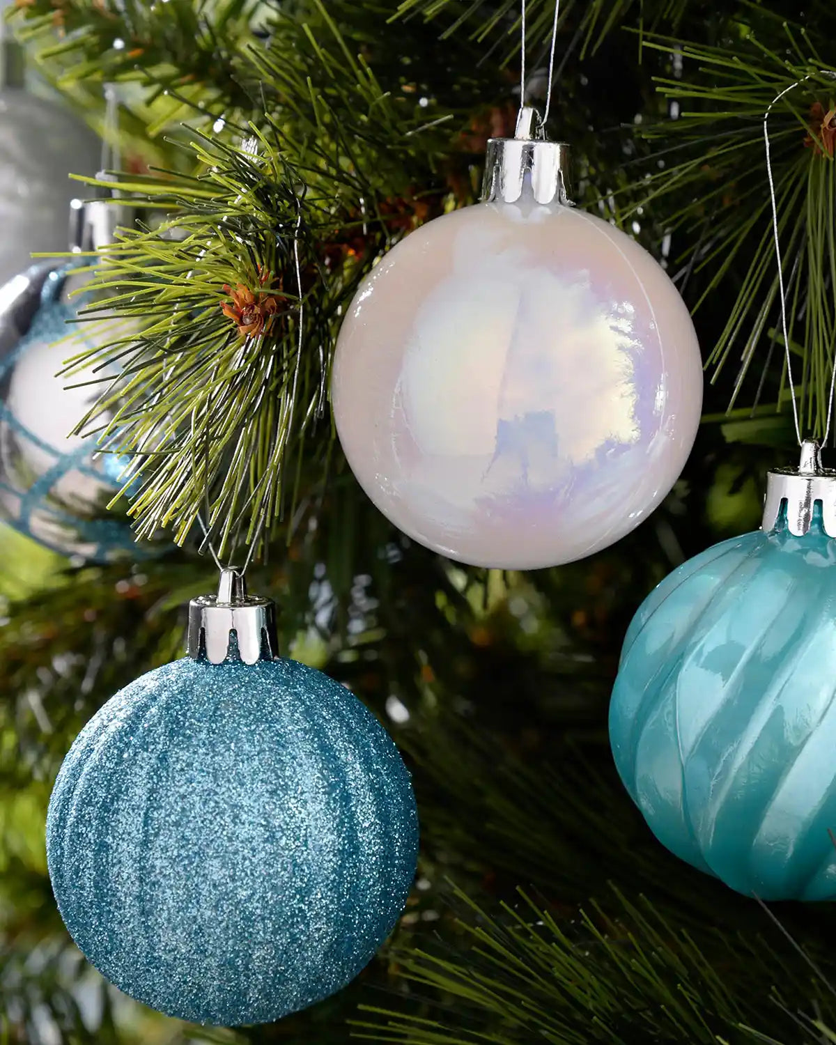 Blue, white and silver 6cm shatterproof baubles hanging on a green Christmas tree