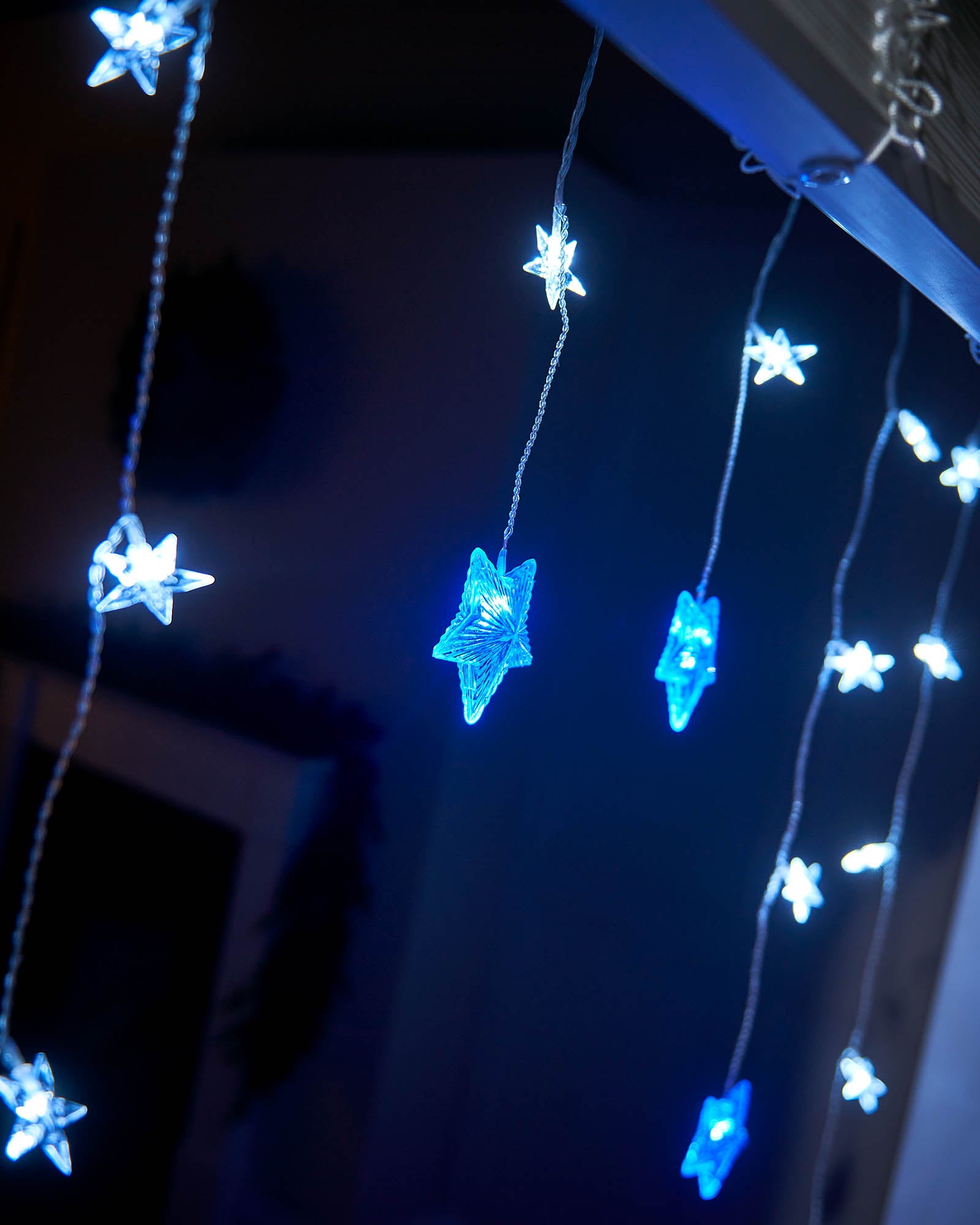 Blue and white star curtain net lights hanging from a window frame