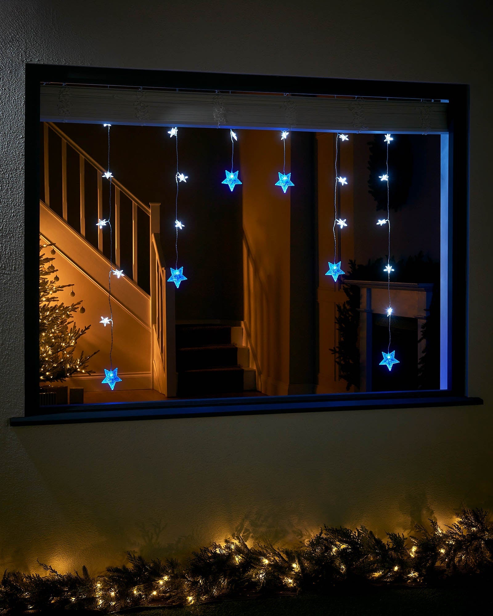 Blue and white star curtain net lights displayed in a window at night