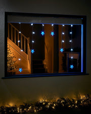 Blue and white star curtain net lights displayed in a window at night