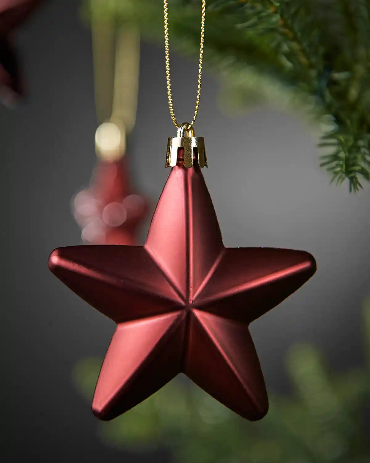Close-up of a matte burgundy 7cm hanging star with gold string.
