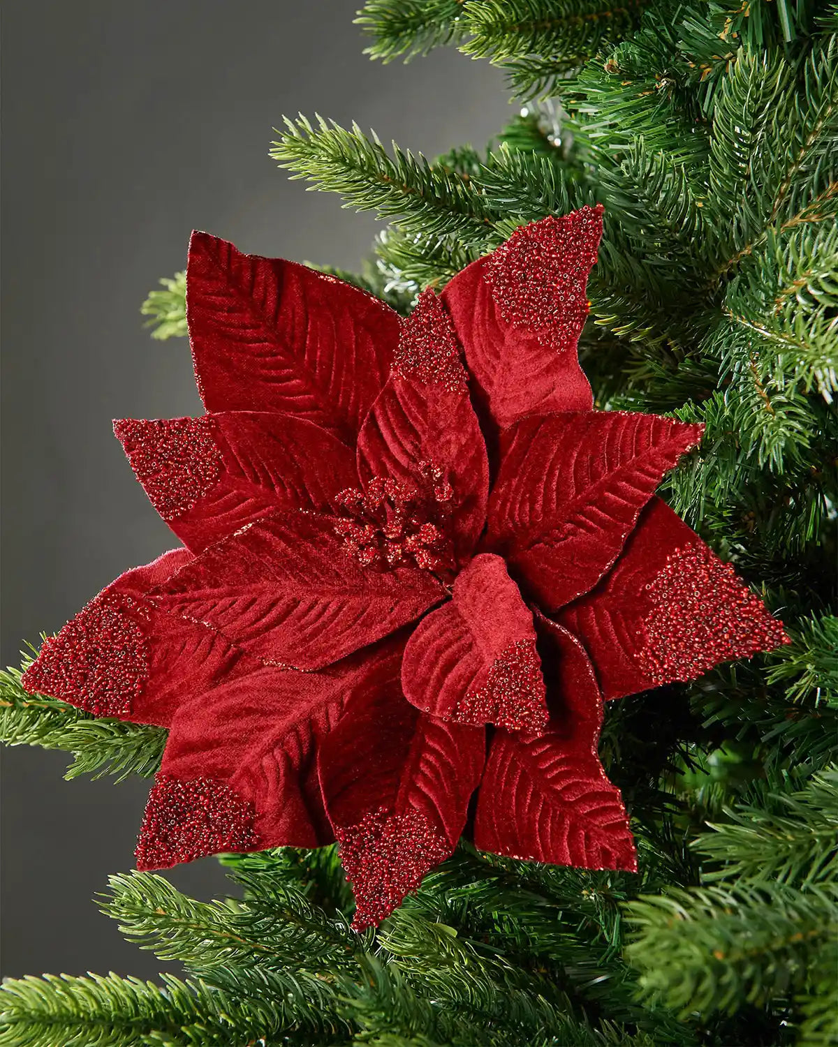 32 cm burgundy artificial poinsettia flower displayed in a Christmas tree, with velvet-textured petals and red glitter accents.
